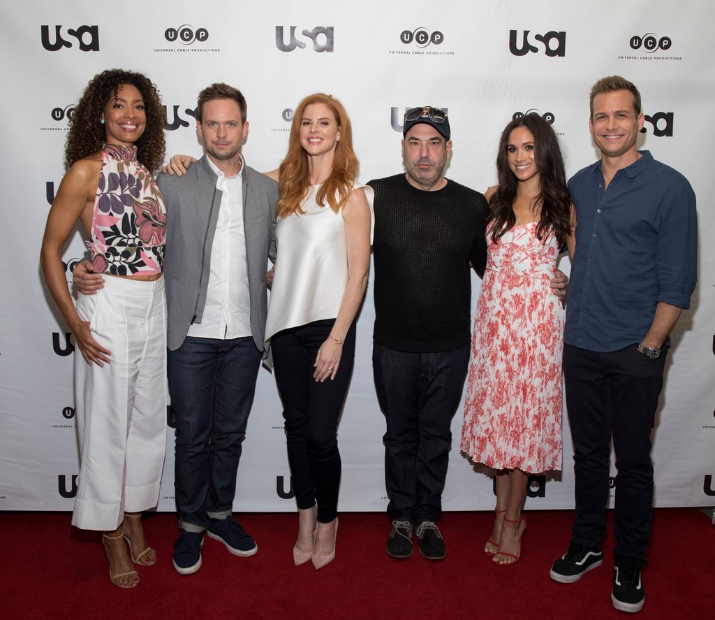 Gina Torres, Patrick J Adams, Sarah Rafferty, Rick Hoffman, Meghan Markle and Gabriel Macht standing in a line